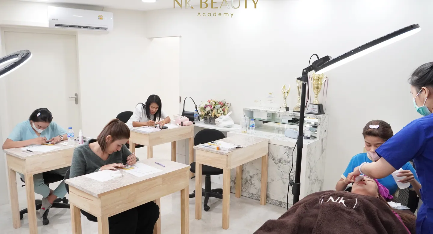 The NK Beauty Academy training room in Phuket: students at the benches, the competition trophies on the shelf and a model being worked on