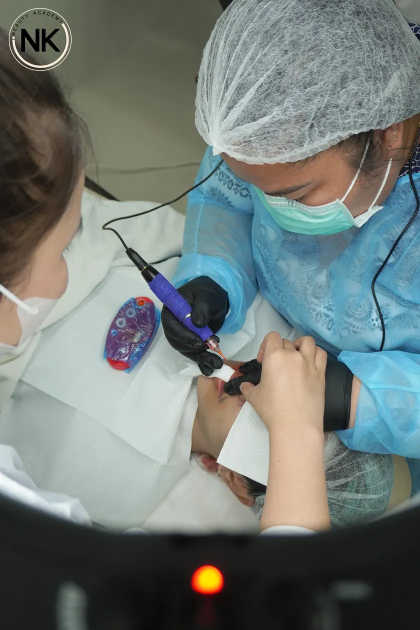 A student working with a permanent makeup machine on a live model