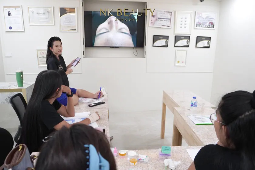 A theory session at NK Beauty Academy, the instructor working through the material with the group