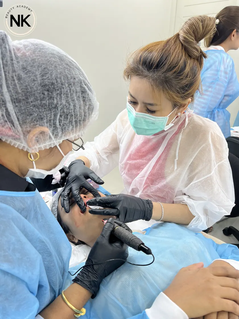 A student working with a permanent makeup machine on a live model