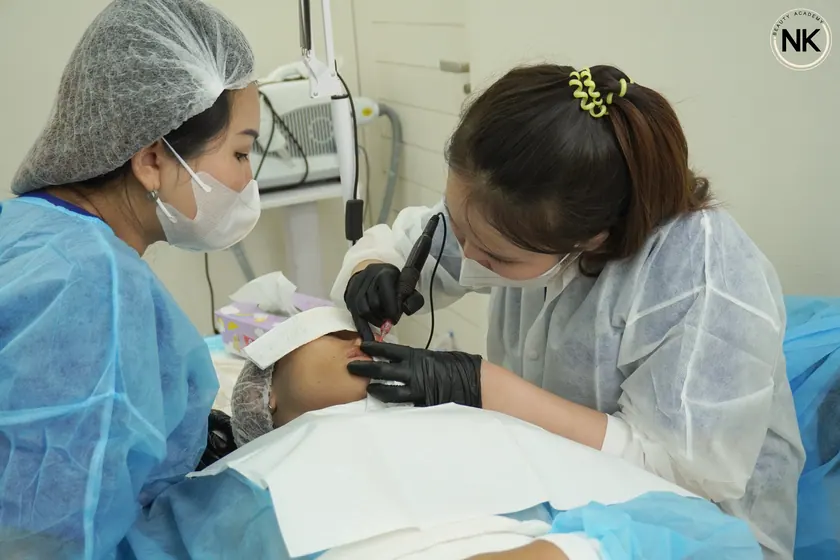 An instructor supervising a student working on a live model