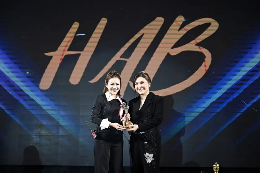 Two artists holding a trophy on the HAB Thailand Contest stage