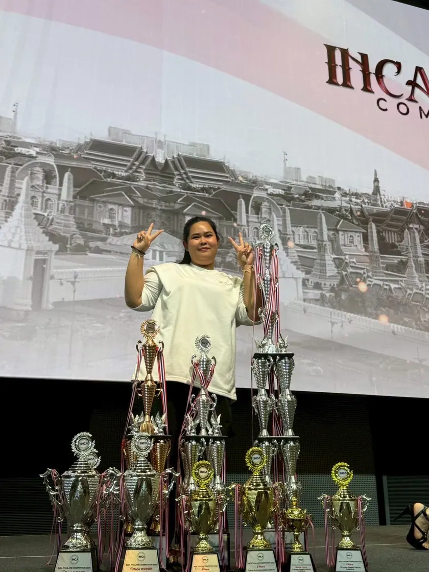 An artist with a display of INCA competition trophies
