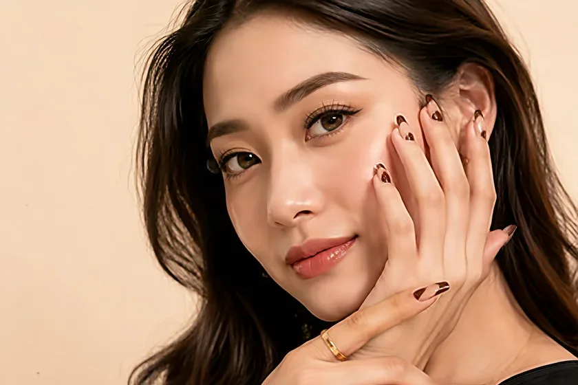 A woman resting a manicured hand against her face